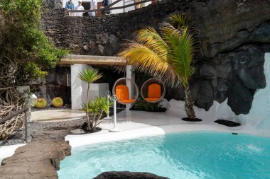 Lanzarote 'deki Cesar Manrique Vakfı' nın manzarası. Sallanan sandalyeler ve yemyeşil yeşilliklerle dolu bir havuz..