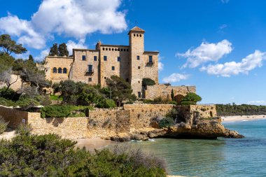 Altafulla, Tarragona, İspanya 'daki etkileyici Tamarit Şatosu güneşli bir günde Akdeniz' e bakan bir uçurumun kenarında duruyor. Mavi gökyüzü ve beyaz bulutlar..