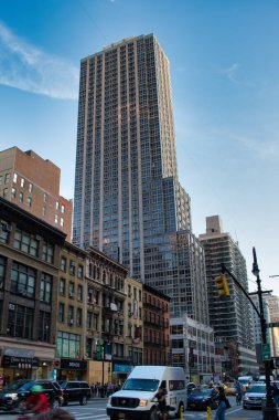 New York şehrinin yüksek açılı sokak manzarası, açık mavi gökyüzü ile eski ve modern mimarinin bir karışımını sergiliyor..