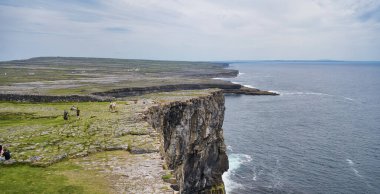 İrlanda 'da okyanus manzaralı bir uçurum manzarası. İnsanlar manzaranın tadını çıkarıyor..
