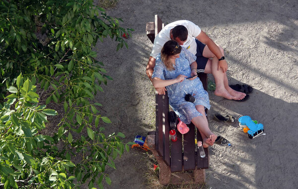 Kyiv, Ukraine June 20, 2022: Parents man and woman watch the phone while their children play in the playground