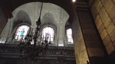 Paris, Fransa 'daki Saint-Sulpice Kilisesi' nin görkemli manzarası, yüksek kemerli bir tavan, vitraylı pencereler ve bir avize içeriyor..