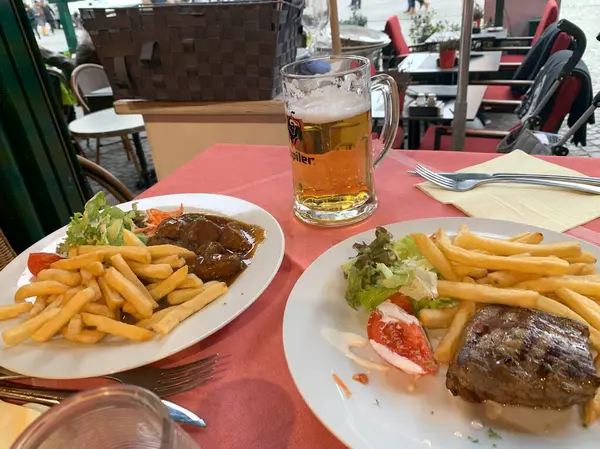 İki tabak biftek ve patates kızartmasının ağız sulandırıcı bir fotoğrafı. Yanında da ferahlatıcı bir bardak bira. Biftekler mükemmel pişmiş, patates kızartmaları da altın sarısı ve çıtır çıtır..