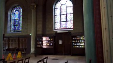 İçinde vitray pencereler, kemerli sütunlar ve ahşap sıralar bulunan bir kilisenin içi. Kilise loş bir şekilde aydınlatılmış, huzurlu ve düşünceli bir atmosfer yaratıyor..