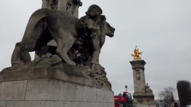Fransa 'nın Paris kentindeki Pont Alexandre Köprüsü' ndeki görkemli aslan heykelinin yakın plan görüntüsü. Altın bir heykel ve arka planda hareketli bir şehir..