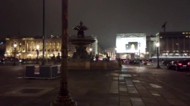 Fransa, Paris 'teki Place de la Concorde' un gece manzarasında ikonik çeşme, Meclis Ulusal Binası ve hareketli şehir hayatı yer alıyor..