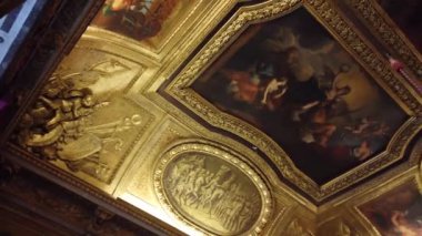 Fransa 'nın Versay Sarayı' nın altın yaprak ve karmaşık detaylarla süslenmiş süslü tavanının yakın görüntüsü..