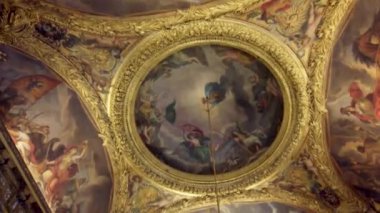  Fransa 'nın Versailles Sarayı' nın süslü tavanının yakından görüntüsü, altın yaprak ve mitolojiden bir sahneyi resmeden merkezi bir tablo..