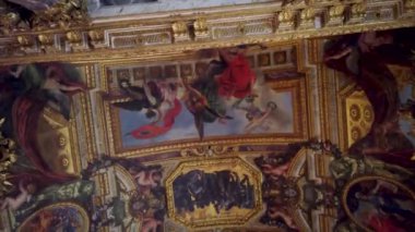 Fransa 'nın Versailles Sarayı' nın süslü tavanının yakından görüntüsü, altın yaprak ve figürler ve hayvanlarla dolu mitolojik bir sahneyi tasvir eden merkezi bir tablo..