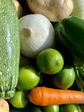 Kabak, soğan, limon, havuç ve patates de dahil olmak üzere çeşitli taze ve renkli sebzeleri gösteren yakın plan bir resim..