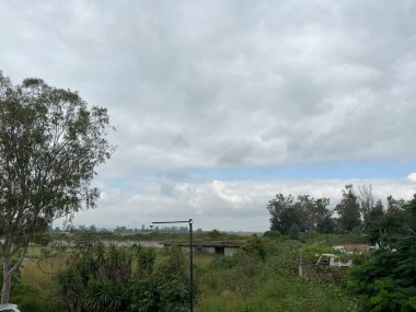 Dramatik, bulutlu bir gökyüzü altında kırsal bir arazinin atmosferik görüntüsü