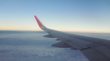 Güzel sabah güneşinde bulutların üzerinde uçarken kabin pencerelerinden uçak kanadı manzarası