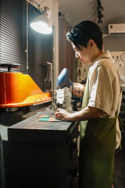 Genç deri ustası çekiç kullanıyor. Deri çatala çarpıyor. Deri ürün üzerinde dikiş deliği açıyor.