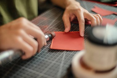 Genç deri işçisi deri yüzeyi hazırlamak için sandık deri ürün öğütme üzerinde çalışıyor.