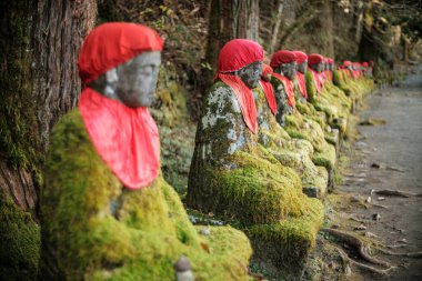 Esrarengiz Obake Jizo heykelleri Nikko 'nun yürüyüş yolunu çiziyor. Yosun kaplı ve yıpranmış bu taş figürler, ormanın ortasında atmosferik, ruhsal bir sahne yaratıyor..