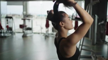 Genç bir kadın ayakta çalışmaya hazırlanırken saçını bağlıyor sağlıklı vücut geliştirme egzersizleri yapıyor..