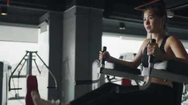 Genç bir kadın spor salonunda bacak kaldırma egzersizi yapıyor..