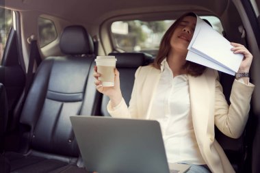 Genç bir kadın çalışırken yüzünü evrak işleriyle örterek arabasındaki işi hakkında kötü haberler alıyor..