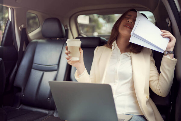 Молодая женщина закрывает лицо бумажной работой, пока работает, и получает плохие новости о своей работе в машине..