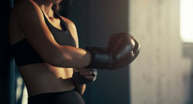 Spor salonunda boks eldiveni giyen genç bir kadın..
