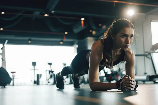 Spor salonunda egzersiz yaparken tahta egzersizi yapan genç bir kadın..