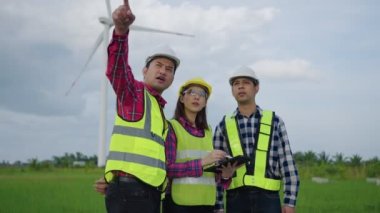 Asyalı mühendislerden oluşan bir ekip rüzgar türbinlerini tartışıyor ve kontrol ediyor. Yenilenebilir enerji teknolojisi ve sürdürülebilirlik.