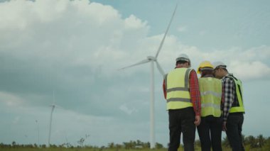Back view of three engineers discussing and progress check wind turbine field.