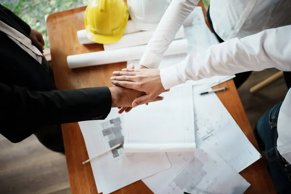 Architects and engineers teamwork join hands together,construction engineer working in construction site, construction engineer conceptual,architect drawing on architectural project on background.