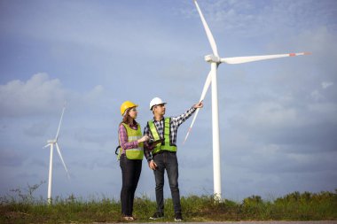 Team of asian engineers discussing and progress check wind turbine field. clipart