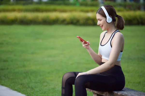Jonge Vrouw Sportkleding Luistermuziek Met Koptelefoon Het Park Zit Een — Stockfoto