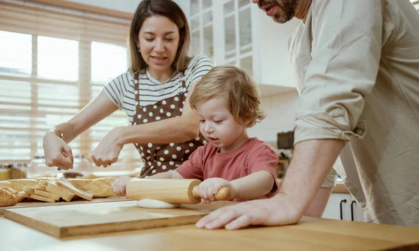 stock image Father and mother teaching baby son kneading dough on kitchen counter at home. Parents and boy kid enjoy and fun indoors activity cooking together.