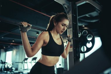 Spor salonunda ağırlık plakasıyla egzersiz yapan sporcu bir kadın..