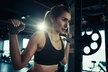 Spor salonunda ağırlık plakasıyla egzersiz yapan sporcu bir kadın..
