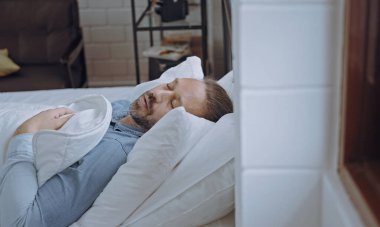 Erkek yatakta uyuyor. Yatak odasında..