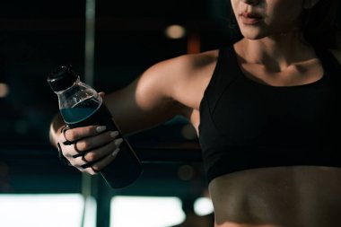 Spor salonundaki eğitimden sonra elinde su şişesi tutan ve dinlenen sportif kadın..