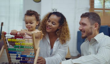 Baba, anne ve kız bir oyuncak oynuyorlar ve oturma odasında eğleniyorlar..