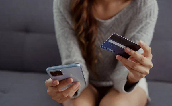 紧紧抓住手里拿着信用卡和智能手机的女人 在网上商店使用银行进入数据购物单进行网上支付的年轻妇女 — 图库照片