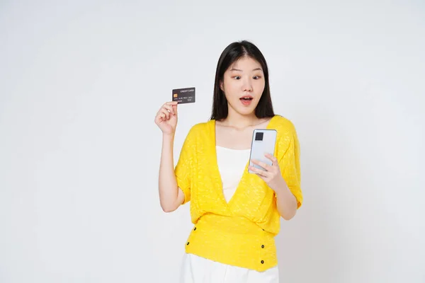 快乐的年轻女人拿着手机拿着信用卡独立的白色背景 — 图库照片