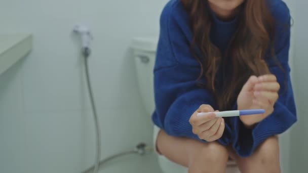 トイレに座って妊娠検査結果を待っているストレスのない女性 — ストック動画