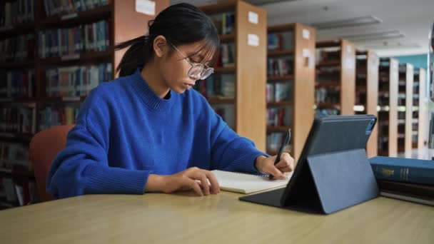 Student Dziewczyna Studiuje Odrabianie Prac Domowych Pomocą Tabletu Bibliotece — Wideo stockowe