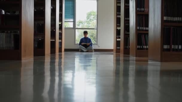 Μαθήτρια Που Κάθεται Στο Πάτωμα Και Διαβάζει Βιβλία Στη Βιβλιοθήκη — Αρχείο Βίντεο