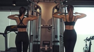 Sporty woman exercising on multistation at gym for arm and shoulders muscles. Fitness exercising in gym.