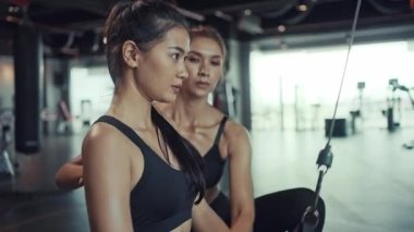 Genç Asyalı kadın spor salonunda egzersiz yapıyor, kişisel antrenörle kaslarını ve gücünü güçlendirmek için egzersiz yapıyor. Spor salonunda spor yapmak..