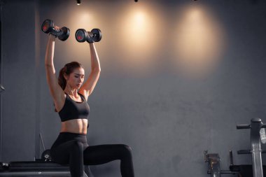 Spor salonunda spor yapan ve halterleri kaldıran Asyalı kadın..