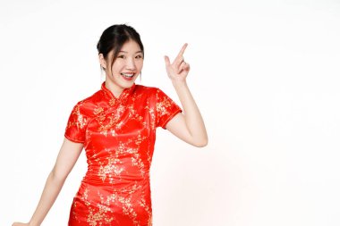 Geleneksel Cheongsam Qipao elbisesi giyen mutlu Asyalı kadın beyaz arka planda izole edilmiş fotokopi alanını işaret ediyor. Mutlu Çin Yeni Yılı