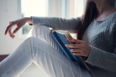 Genç Asyalı üniversite öğrencisi kütüphanede oturmuş kitap okuyor..