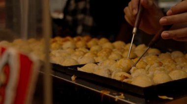 Şef, geleneksel Japon topu şekilli aperatif hazırlıyor. Sokak yiyecek pazarında özel bir demir tavada Takoyaki..