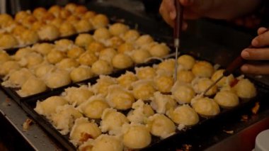 Şef, geleneksel Japon topu şekilli aperatif hazırlıyor. Sokak yiyecek pazarında özel bir demir tavada Takoyaki..