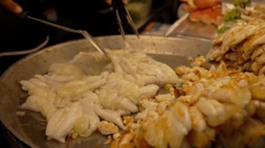 Asyalı sokak yemekleri şefi yerel bir markette kızarmış kalamar yumurtası pişiriyor..