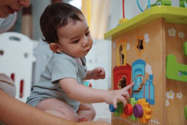 Tatlı Asyalı kadın ve küçük oğlu oturma odasında birlikte eğitici oyuncaklar oynuyorlar. Anne ve oğlu küp oynayıp gülüyorlar. Mutlu aile. Genç anne ve oğlu evde birlikte aktiviteler yapıyorlar..